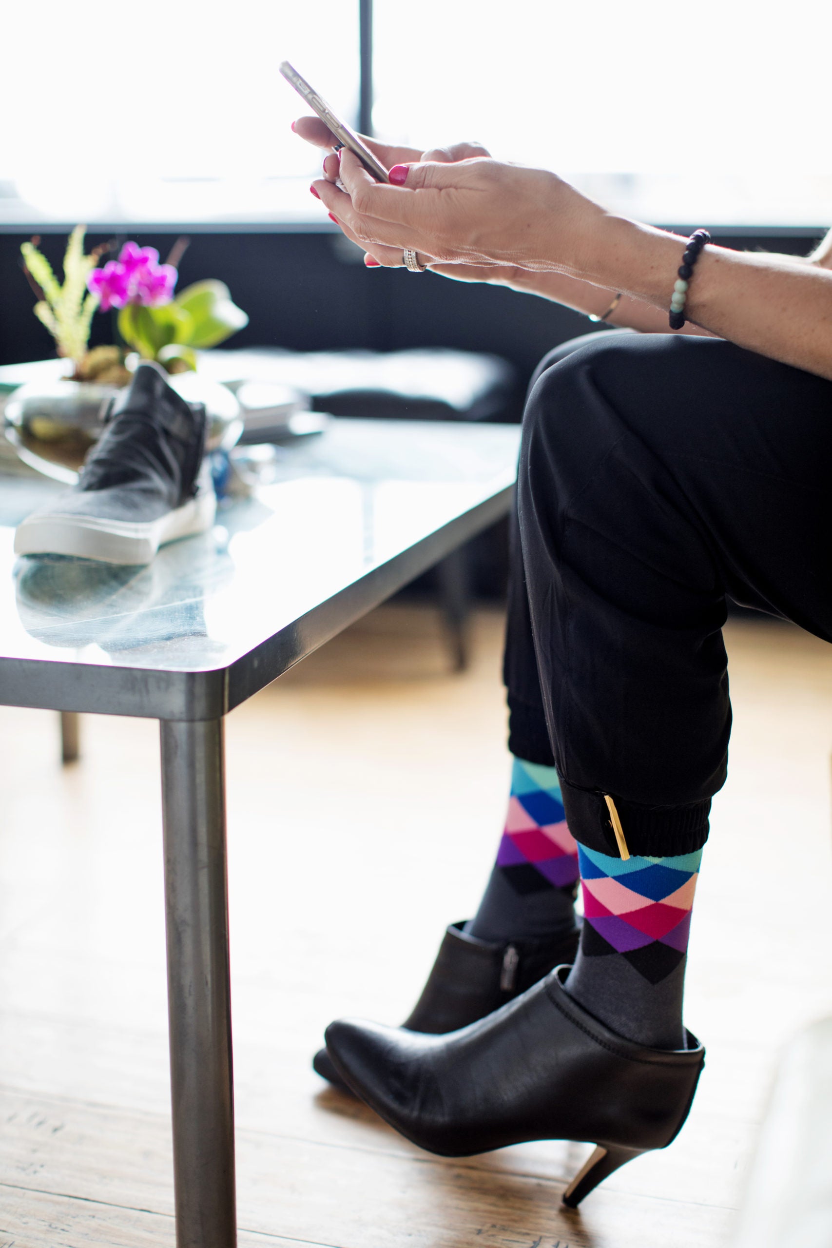 Woman in the office wearing Lunatik Pastel Pixel compression socks with black heels.