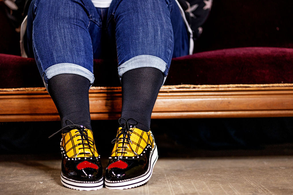 Lower legs of a woman wearing Lunatik Graphite Grey+ compression socks with jeans and laced up shoes.