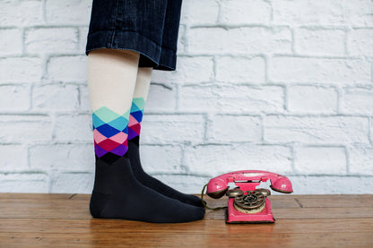 A woman wearing Lunatik Pastel Pixel compression socks in front of a white brick wall.