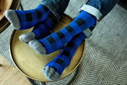 A couple resting their feet in matching Lunatik Lumber Jack compression socks in blue.