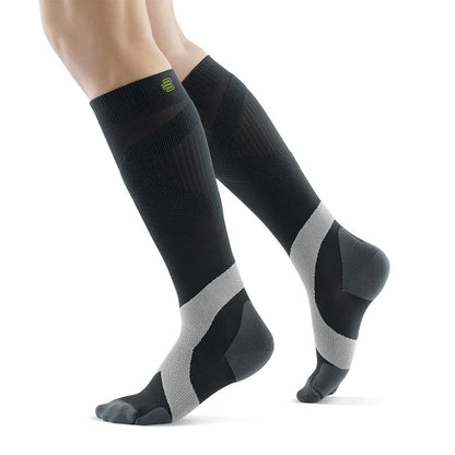 Lower legs of a model in charcoal polar Bauerfeind training compression socks standing in front of a white background.