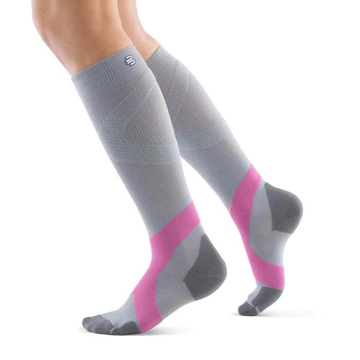 Lower legs of a model in silver pink Bauerfeind training compression socks standing in front of a white background.