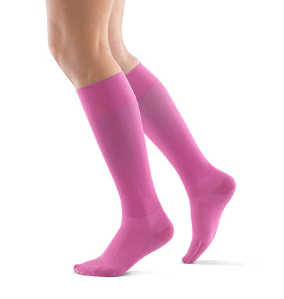 Lower legs of a model in pink Bauerfeind performance compression socks standing in front of a white background.