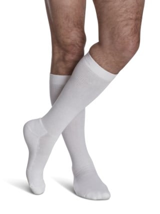 Legs of male model in knee-length Sigvaris Cushioned Cotton compression calf socks in white.