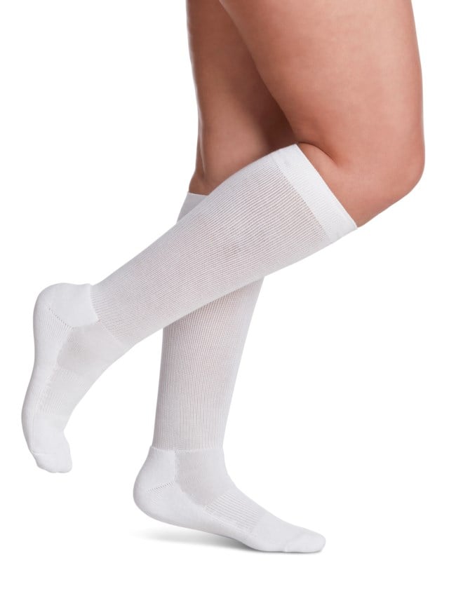 Legs of female model in knee-length Sigvaris Cushioned Cotton compression calf socks in white.