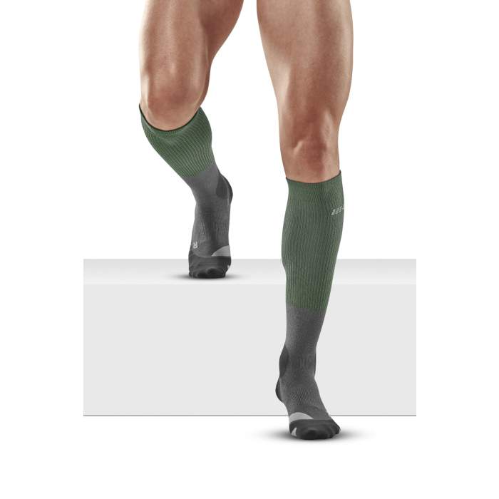 Lower legs of male model walking in knee-high CEP Hiking Merino compression socks in green grey.