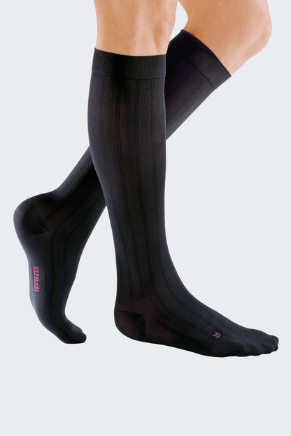 Lower legs of model in knee-high Mediven Men's dress compression socks in black.