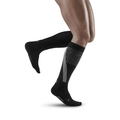 Lower legs of male model running in knee-high CEP Cold Weather compression socks in black.