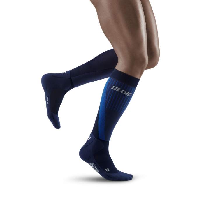 Lower legs of male model running in knee-high CEP Cold Weather compression socks in navy.