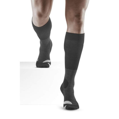 Lower legs of male model walking in knee-high CEP Hiking Merino compression socks in stone grey.