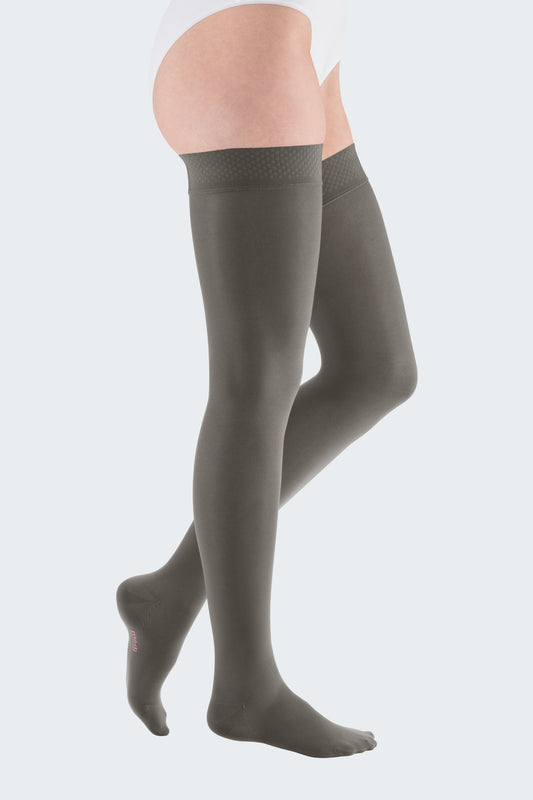 Lower body of female model in thigh-length Mediven Elegance compression tights in grey. 