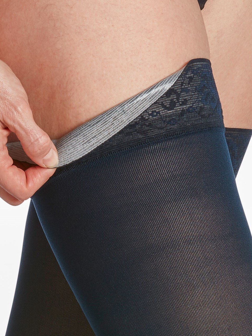 Close-up of lace detail on thigh-high Sigvaris Soft Opaque compression tights in black.