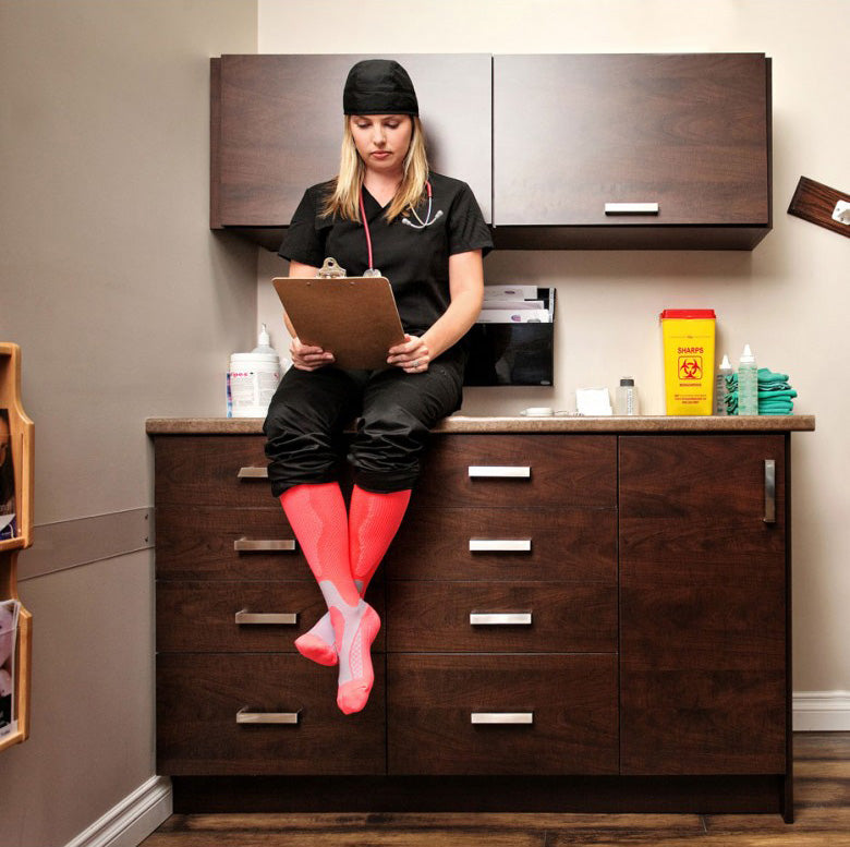 Medical worker in black scrubs and Lunatik Vibe Tech compression socks in pink.