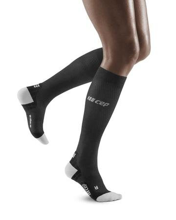 Lower legs of model in knee-high CEP Ultralight Running compression socks in black, with white toes and heels (side view).