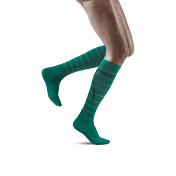 Lower legs of model in knee-high CEP Reflective running compression socks in green.