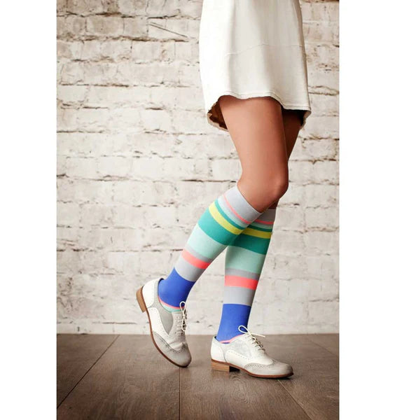 Female model in white skirt, Lunatik Urbane Stripe compression socks, and white oxfords.