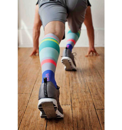 Model wearing Lunatik Urbane Stripe compression socks and running shoes in running start pose.