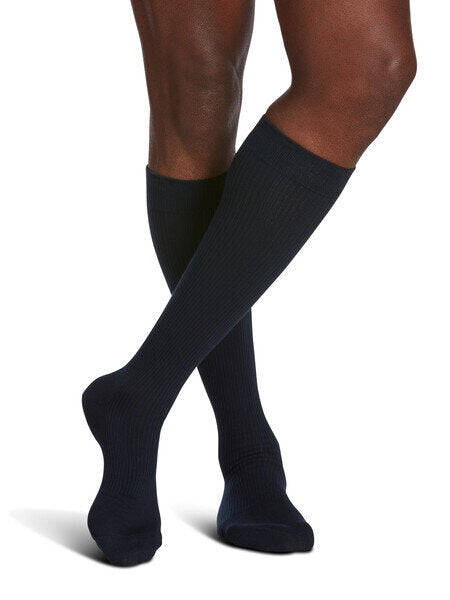 Legs of model in navy Sigvaris Casual Cotton compression socks on white background.