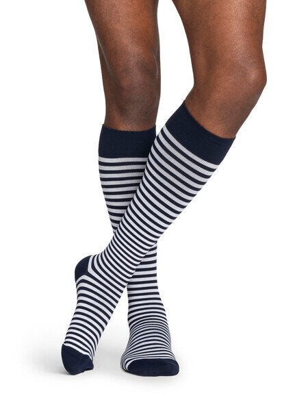 Legs of model in knee-length Sigvaris Mariner Microstripe compression socks on white background.