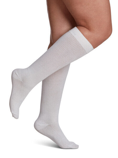 Legs of model in white Sigvaris Casual Cotton compression socks on white background.