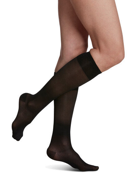 Legs of model in Sigvaris Sheer compression calf socks in black.